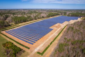 Aerial view of a large-scale commercial ground mount solar farm featuring long rows of photovoltaic panels installed on cleared land.